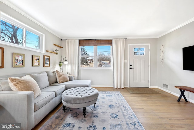 living room featuring a wealth of natural light, light wood-style floors, and crown molding