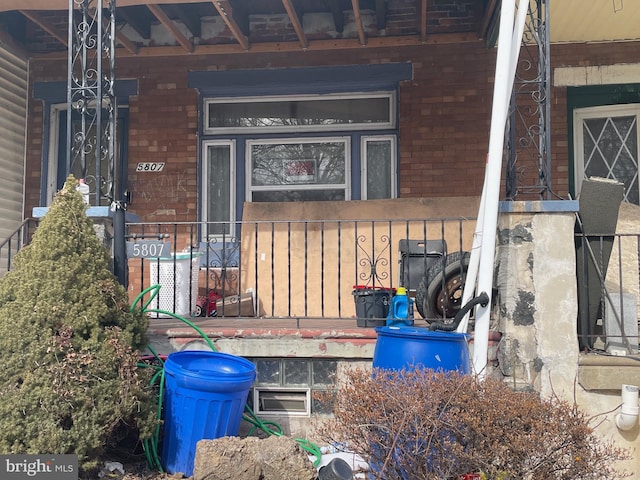 entrance to property featuring covered porch and brick siding