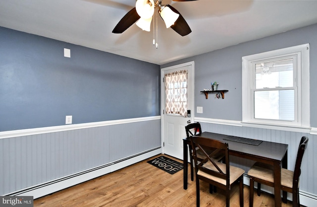 dining room with hardwood / wood-style flooring, a baseboard heating unit, and a healthy amount of sunlight