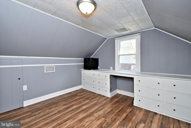 bonus room featuring lofted ceiling, dark hardwood / wood-style flooring, and built in desk