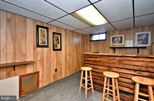 bar with a drop ceiling and wood walls