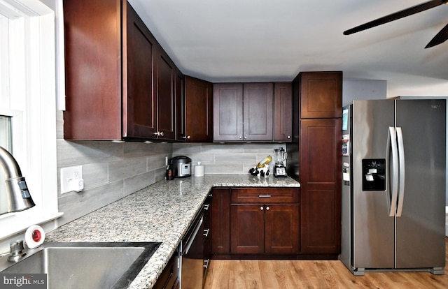 kitchen with light stone counters, light wood-type flooring, ceiling fan, stainless steel appliances, and decorative backsplash