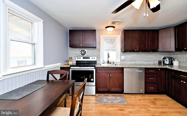 kitchen featuring appliances with stainless steel finishes, light stone countertops, decorative backsplash, light hardwood / wood-style floors, and sink