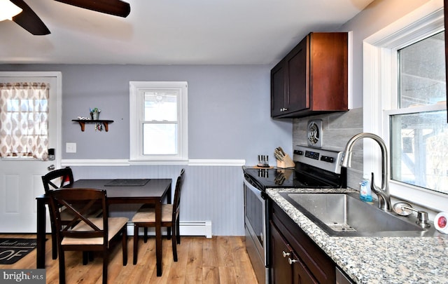 kitchen featuring stainless steel electric range, light hardwood / wood-style flooring, light stone counters, decorative backsplash, and sink