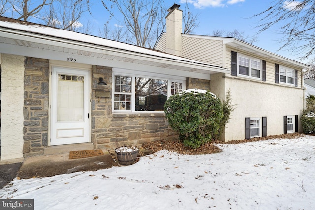 exterior space with stone siding and a chimney