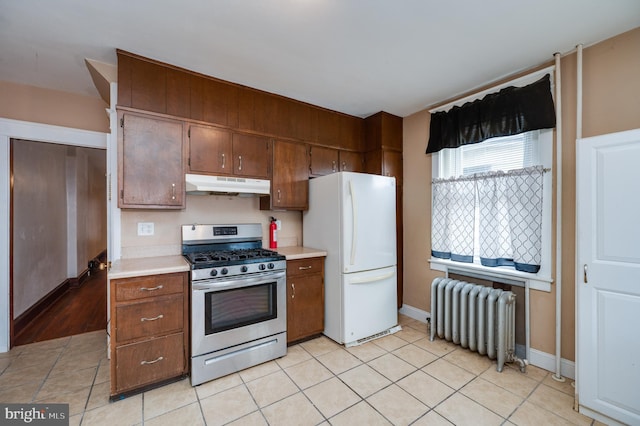 kitchen with white fridge, light tile patterned flooring, radiator, and stainless steel gas stove