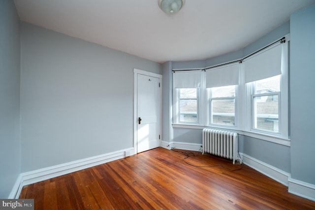 empty room featuring hardwood / wood-style flooring and radiator heating unit