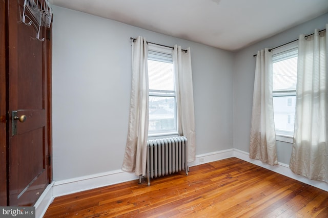 unfurnished room with radiator, hardwood / wood-style floors, and a wealth of natural light