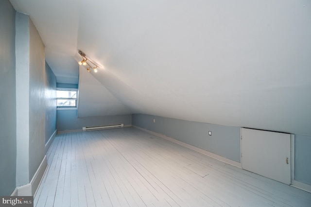 additional living space featuring light wood-type flooring, lofted ceiling, and a baseboard radiator