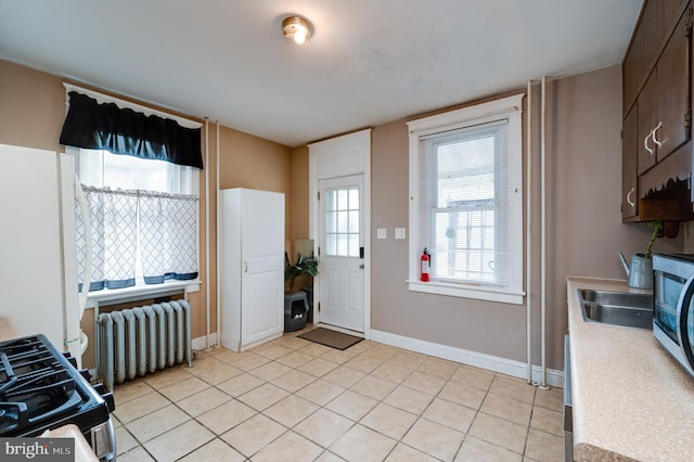 interior space featuring light tile patterned floors, sink, and radiator heating unit