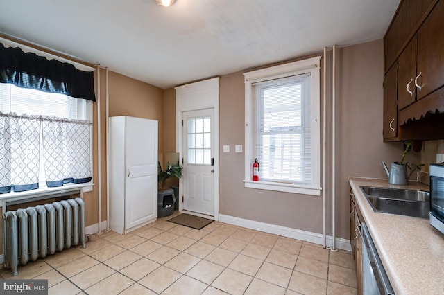 entrance foyer with radiator heating unit, sink, and light tile patterned flooring