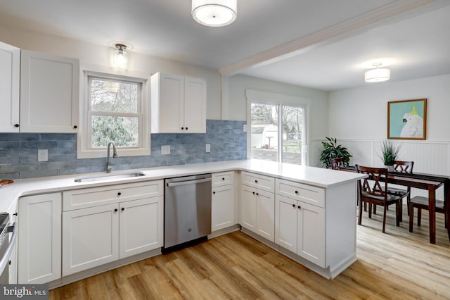 kitchen with a sink, white cabinetry, light countertops, dishwasher, and plenty of natural light