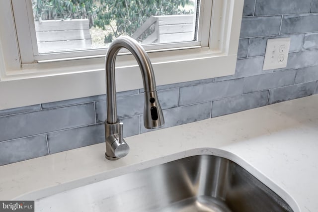 details with light stone counters, backsplash, and a sink