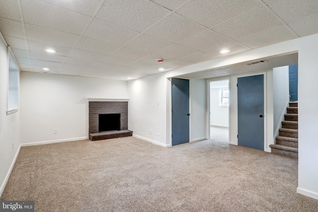 basement featuring carpet floors, a brick fireplace, baseboards, and visible vents