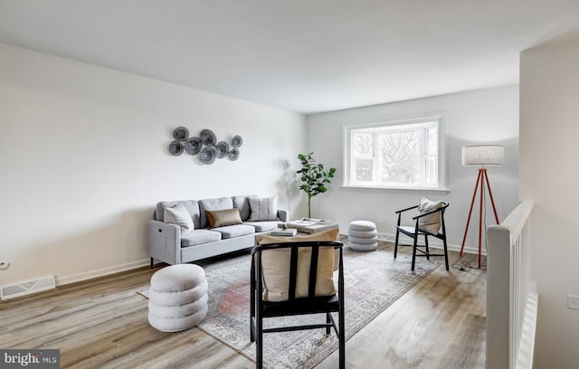 living area with baseboards, visible vents, and light wood finished floors