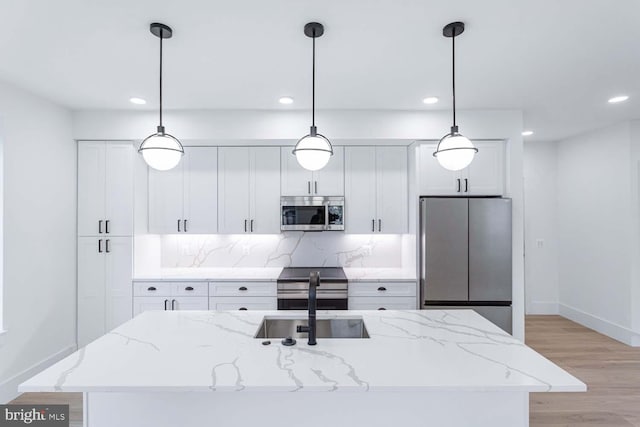 kitchen featuring appliances with stainless steel finishes, pendant lighting, and a kitchen island with sink