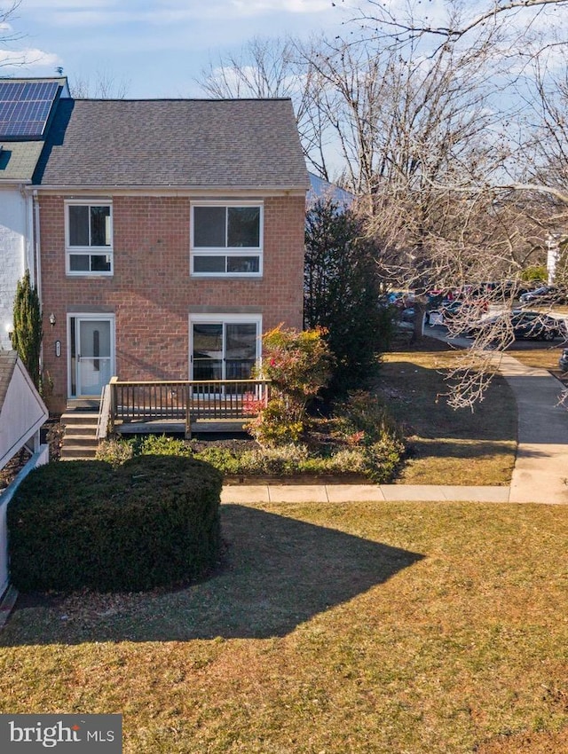 exterior space featuring a deck, brick siding, and a lawn