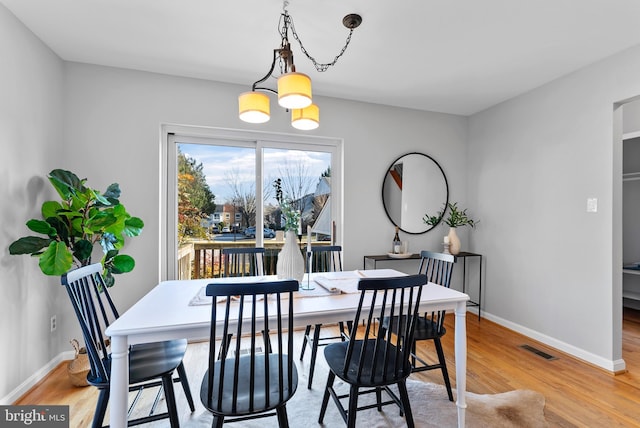 dining room featuring visible vents, a notable chandelier, baseboards, and wood finished floors