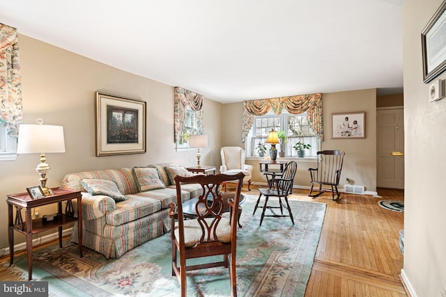 living room featuring visible vents, baseboards, and wood finished floors