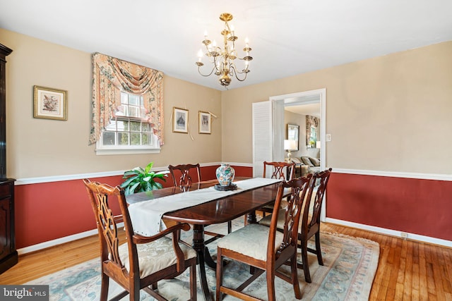 dining area with light wood-style flooring, baseboards, and an inviting chandelier