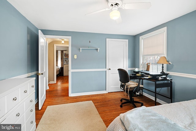 bedroom with baseboards, ceiling fan, wood finished floors, and a closet