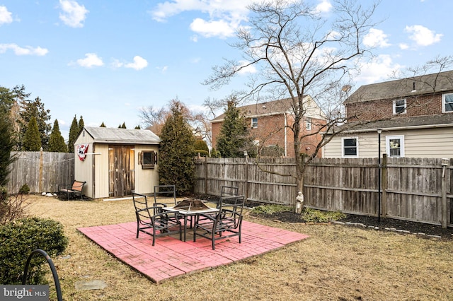 view of yard with an outdoor fire pit, an outbuilding, a patio area, a shed, and a fenced backyard