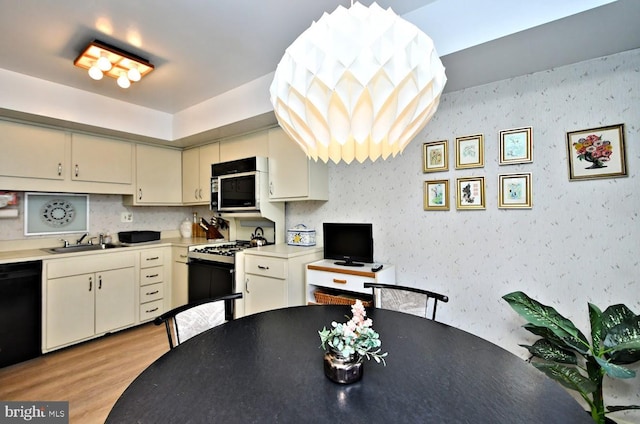 kitchen with sink, dishwasher, range with gas stovetop, light hardwood / wood-style floors, and cream cabinets