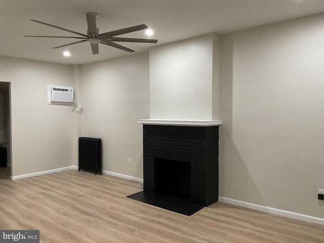 unfurnished living room with an AC wall unit, light hardwood / wood-style floors, ceiling fan, and a fireplace