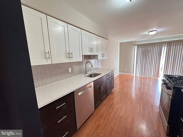 kitchen with appliances with stainless steel finishes, sink, white cabinets, and light hardwood / wood-style floors