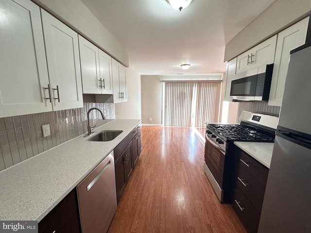 kitchen featuring light hardwood / wood-style flooring, sink, backsplash, white cabinetry, and stainless steel appliances