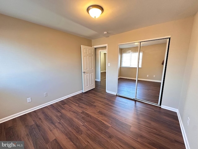 unfurnished bedroom with dark hardwood / wood-style flooring and a closet