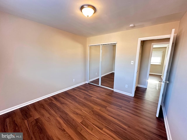 unfurnished bedroom with dark hardwood / wood-style floors and a closet