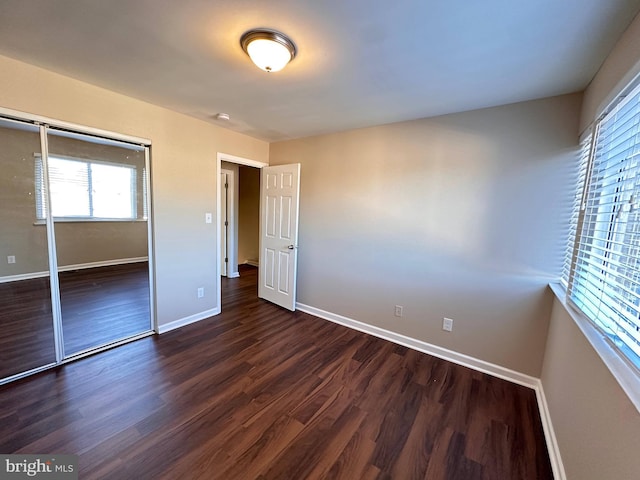 unfurnished bedroom with dark wood-type flooring and a closet