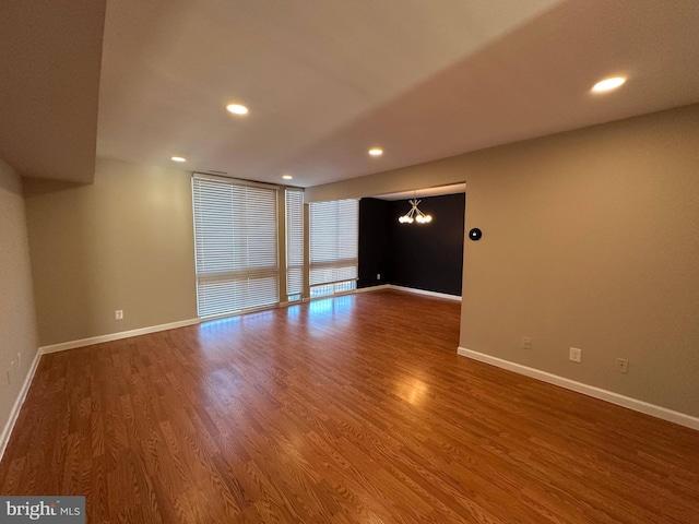 spare room featuring a wall of windows, hardwood / wood-style flooring, and a chandelier