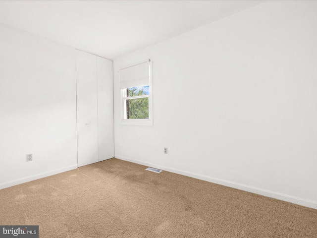 carpeted spare room with visible vents and baseboards