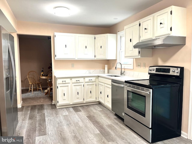 kitchen featuring under cabinet range hood, a sink, light countertops, appliances with stainless steel finishes, and light wood finished floors