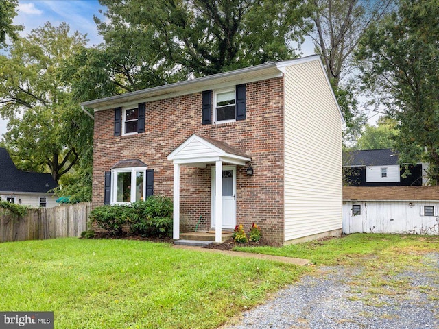 view of front of property featuring fence, a front lawn, and brick siding