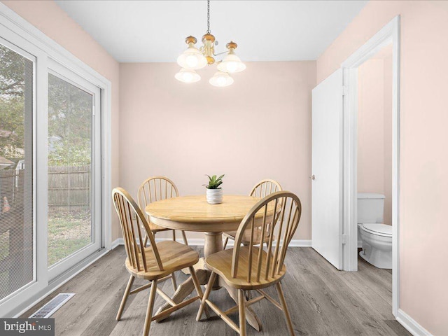 dining room featuring a healthy amount of sunlight, visible vents, and wood finished floors