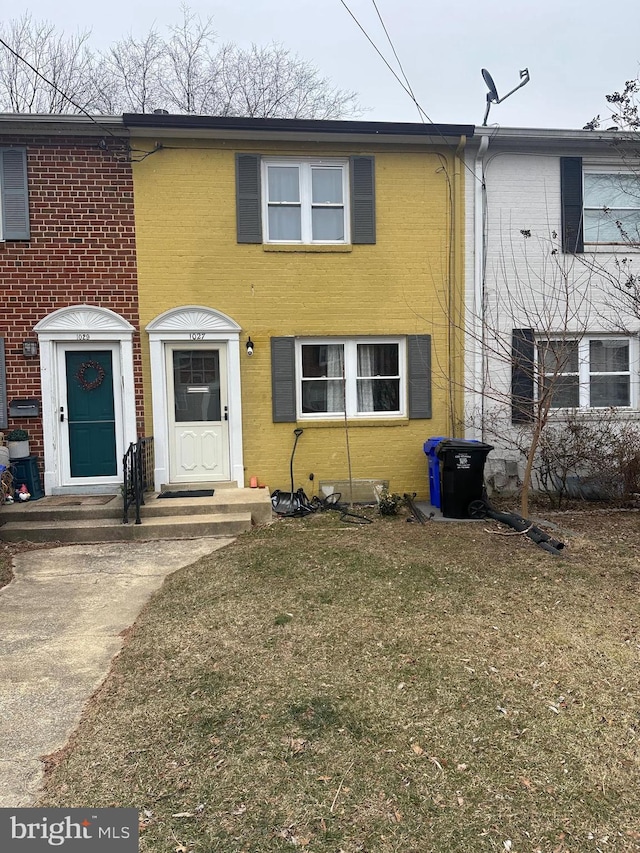 view of front of house featuring entry steps, brick siding, and a front yard