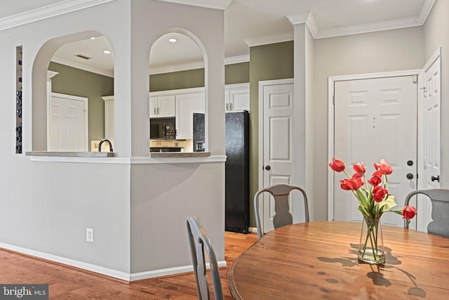 dining room featuring arched walkways, ornamental molding, recessed lighting, and light wood-style floors