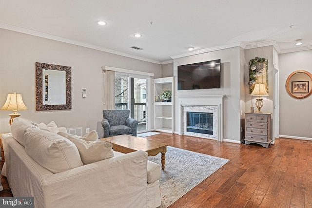 living area with ornamental molding, hardwood / wood-style floors, a premium fireplace, and visible vents