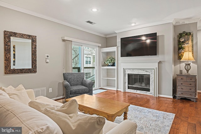 living area featuring a high end fireplace, visible vents, crown molding, and hardwood / wood-style flooring