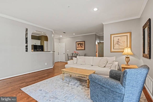 living room with baseboards, arched walkways, wood finished floors, crown molding, and recessed lighting