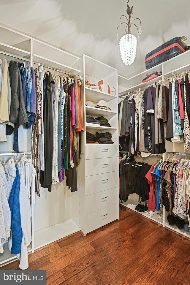 spacious closet with a notable chandelier and wood finished floors