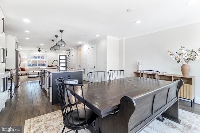 dining room with dark wood finished floors, ceiling fan, recessed lighting, and ornamental molding