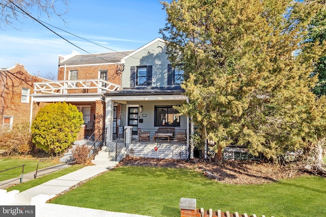 view of front of property with brick siding, a porch, a balcony, and a front yard