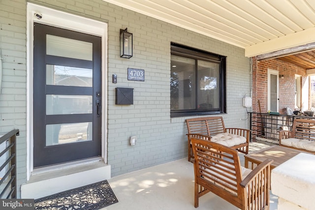 doorway to property featuring brick siding and a porch