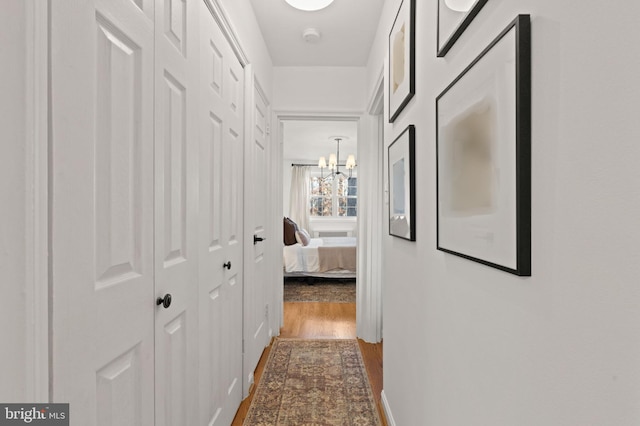 corridor featuring hardwood / wood-style flooring and an inviting chandelier