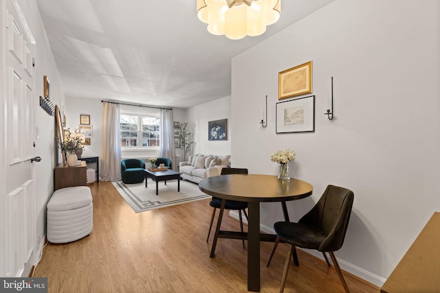 dining space featuring light wood-type flooring and a notable chandelier