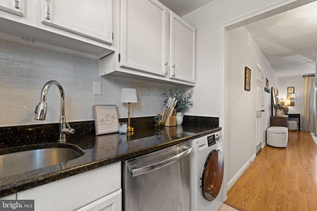 kitchen with sink, white cabinetry, dark stone counters, washer / dryer, and stainless steel dishwasher